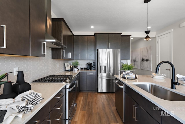 kitchen with dark wood-type flooring, a sink, stainless steel appliances, dark brown cabinetry, and wall chimney exhaust hood