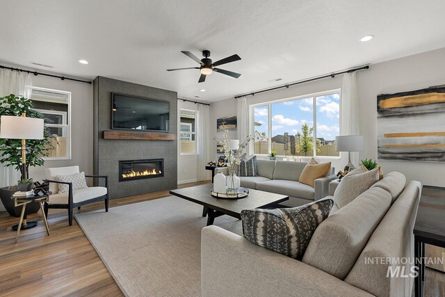 living area featuring recessed lighting, wood finished floors, visible vents, and a large fireplace