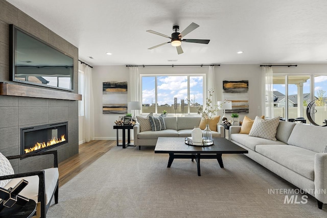 living room with a wealth of natural light, wood finished floors, recessed lighting, and a tile fireplace