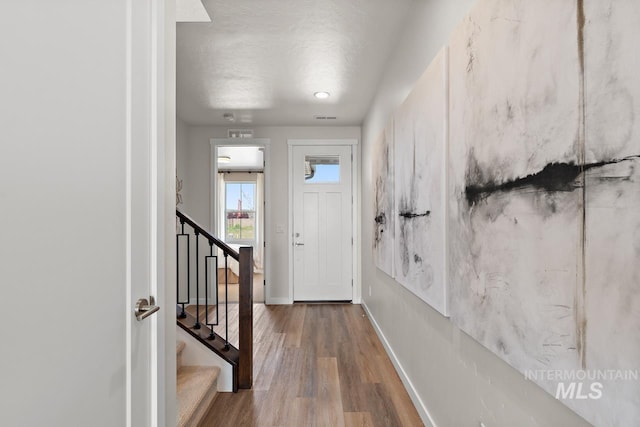 entrance foyer with baseboards, wood finished floors, and stairs