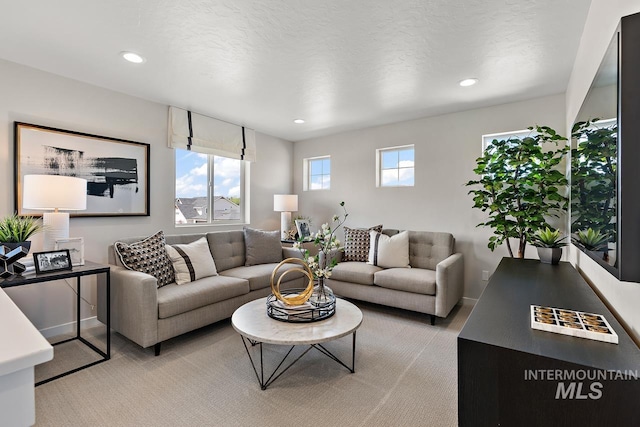 living room with recessed lighting, a textured ceiling, light colored carpet, and baseboards