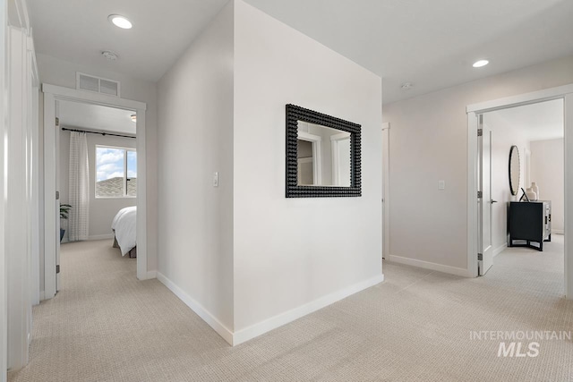 hallway with recessed lighting, light colored carpet, visible vents, and baseboards