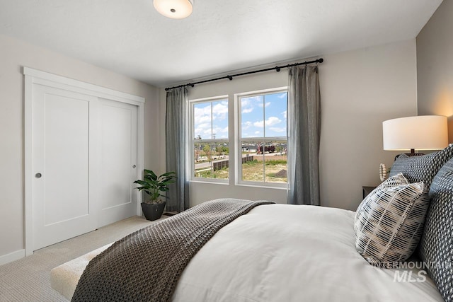 carpeted bedroom with a closet and baseboards