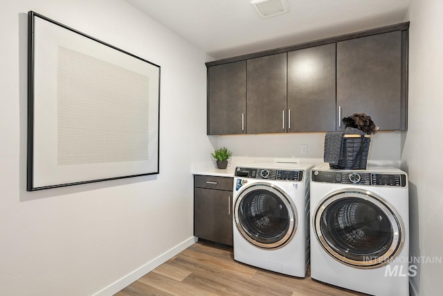 laundry room with visible vents, light wood-style flooring, washing machine and dryer, cabinet space, and baseboards