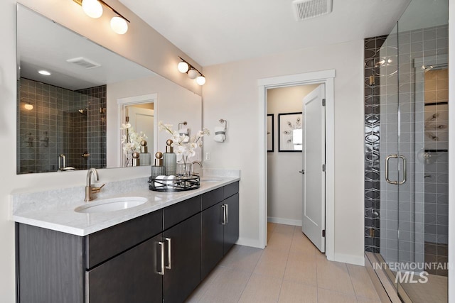 bathroom with double vanity, visible vents, a stall shower, and a sink