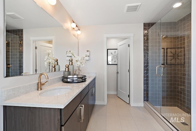 bathroom featuring baseboards, visible vents, double vanity, a stall shower, and a sink