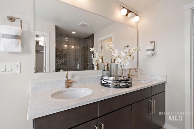 bathroom with double vanity, visible vents, a stall shower, and a sink