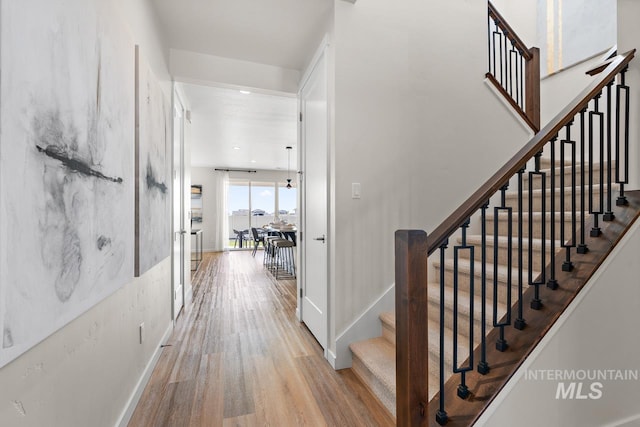 staircase with recessed lighting, wood finished floors, and baseboards