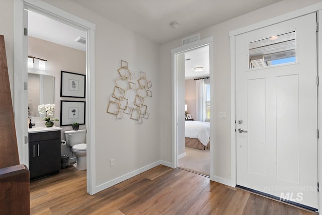 foyer entrance with visible vents, baseboards, and light wood-style floors