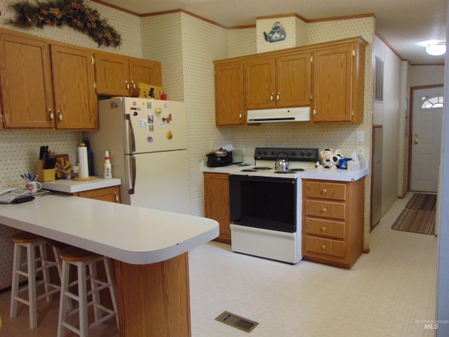 kitchen featuring wallpapered walls, range hood, light countertops, and white appliances