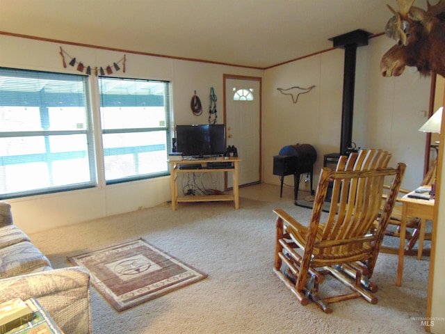 living room featuring ornamental molding, a wood stove, and carpet flooring