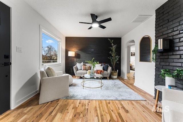 living room with a textured ceiling, light hardwood / wood-style flooring, and ceiling fan