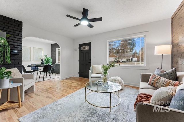 living room with a textured ceiling, wood-type flooring, and ceiling fan