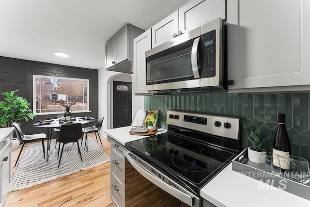 kitchen with stainless steel appliances, gray cabinets, and light wood-type flooring