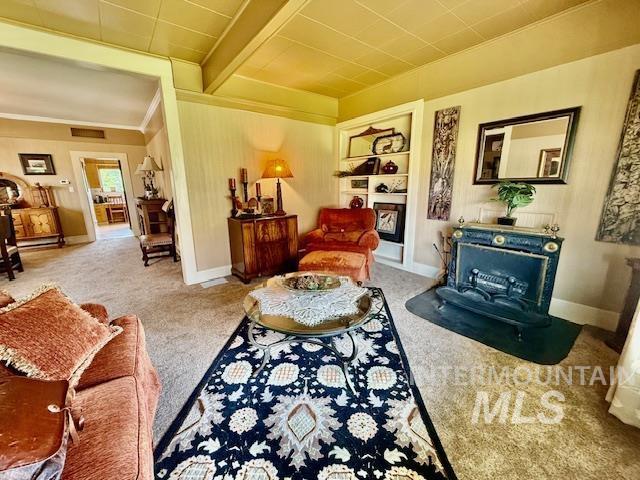 407 1st St, Asotin, WA 99402 - living area with carpet floors, a wood stove, ornamental molding, built in shelves, and beam ceiling