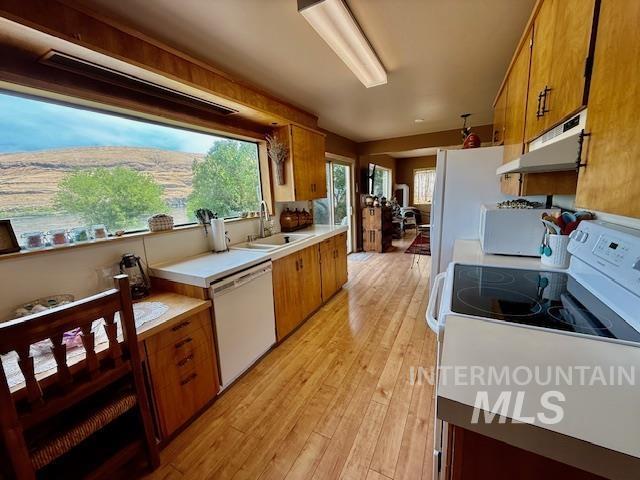 407 1st St, Asotin, WA 99402 - kitchen with white appliances, under cabinet range hood, brown cabinets, light countertops, and plenty of natural light