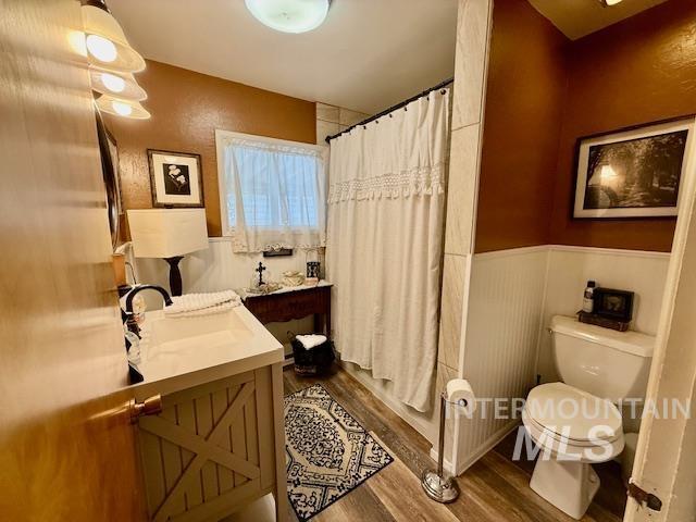 407 1st St, Asotin, WA 99402 - bathroom with wood finished floors, vanity, wainscoting, and shower / bathtub combination with curtain