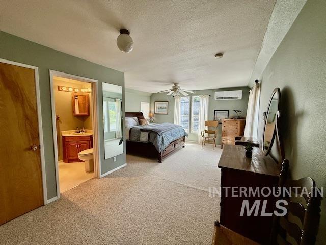 407 1st St, Asotin, WA 99402 - bedroom featuring a wall mounted air conditioner, carpet, a textured ceiling, connected bathroom, and a ceiling fan
