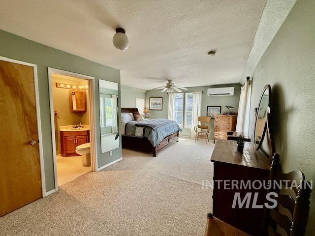 407 1st St, Asotin, WA 99402 - carpeted bedroom with a wall mounted air conditioner, a textured ceiling, ensuite bath, and ceiling fan