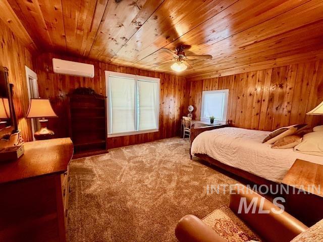407 1st St, Asotin, WA 99402 - bedroom with a wall unit AC, wood ceiling, carpet flooring, and wood walls