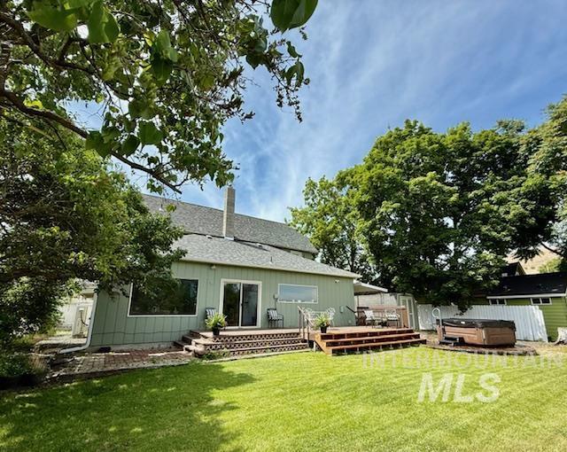 407 1st St, Asotin, WA 99402 - back of property featuring a hot tub, a deck, a lawn, and a chimney