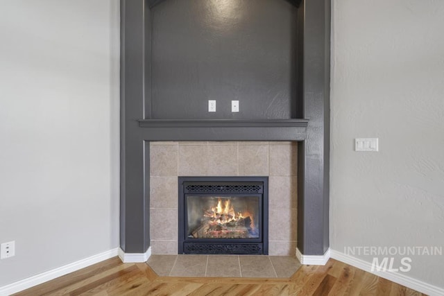 room details featuring baseboards, wood finished floors, and a tiled fireplace