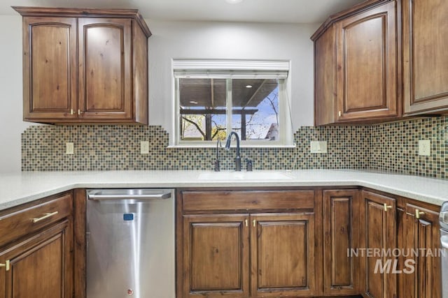 kitchen featuring dishwasher, tasteful backsplash, a sink, and light countertops