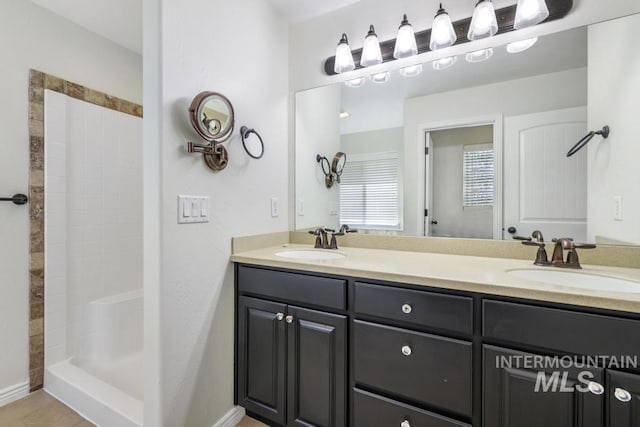 full bathroom with a sink, double vanity, and tiled shower