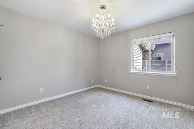 empty room with carpet floors, visible vents, baseboards, and a notable chandelier