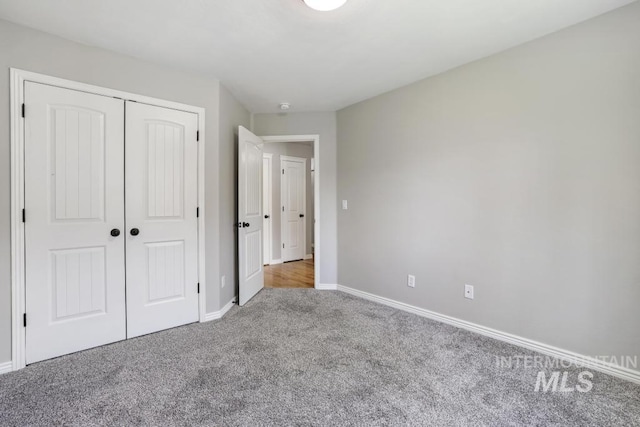 unfurnished bedroom with baseboards, carpet floors, and a closet
