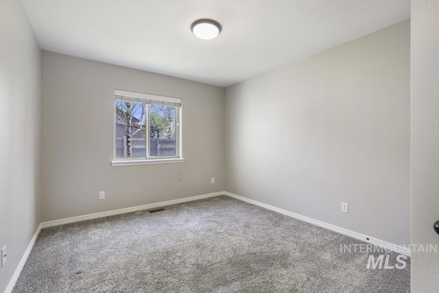 empty room with baseboards, visible vents, and carpet