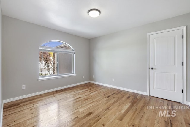 spare room with baseboards and wood finished floors
