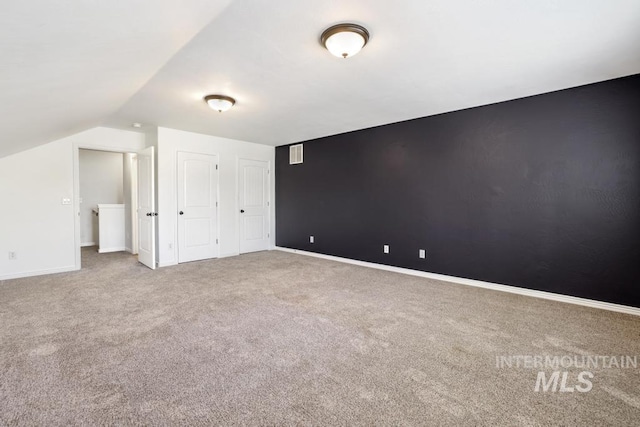 additional living space featuring baseboards, vaulted ceiling, visible vents, and carpet