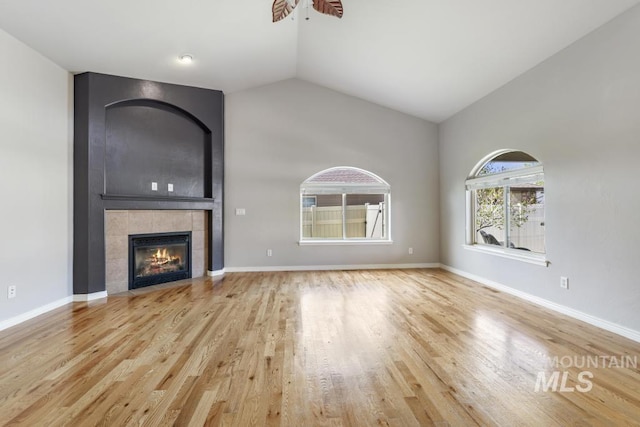 unfurnished living room featuring vaulted ceiling, wood finished floors, ceiling fan, a fireplace, and baseboards