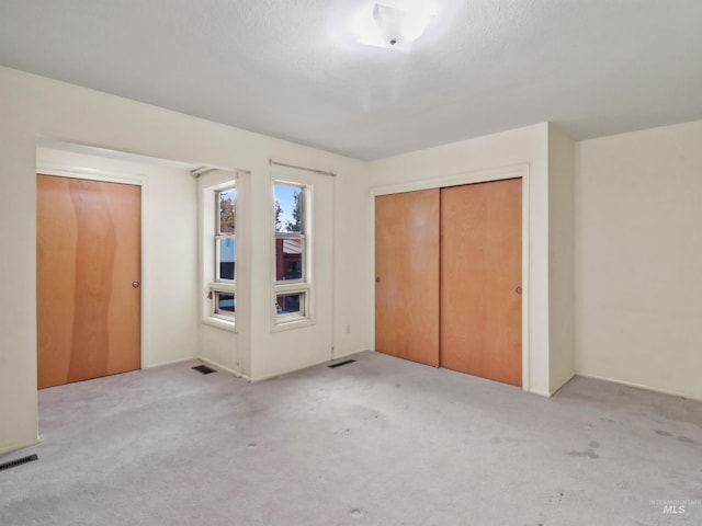 unfurnished bedroom with a textured ceiling and light colored carpet