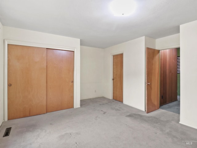 unfurnished bedroom with light colored carpet and a closet