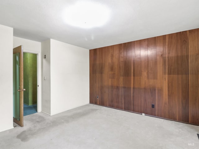 carpeted spare room with wood walls