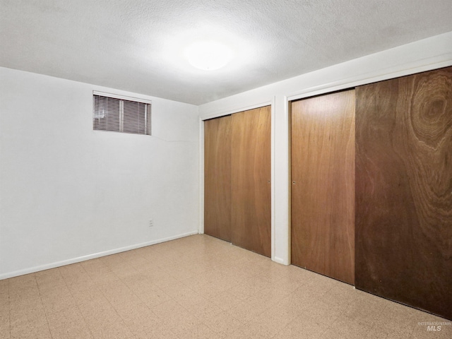 unfurnished bedroom with multiple closets and a textured ceiling