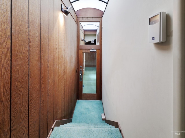 hallway featuring elevator and wooden walls