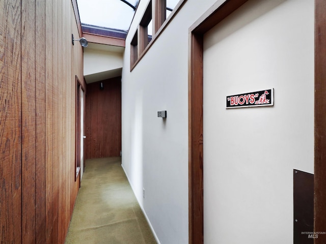 hall with light colored carpet and wooden walls