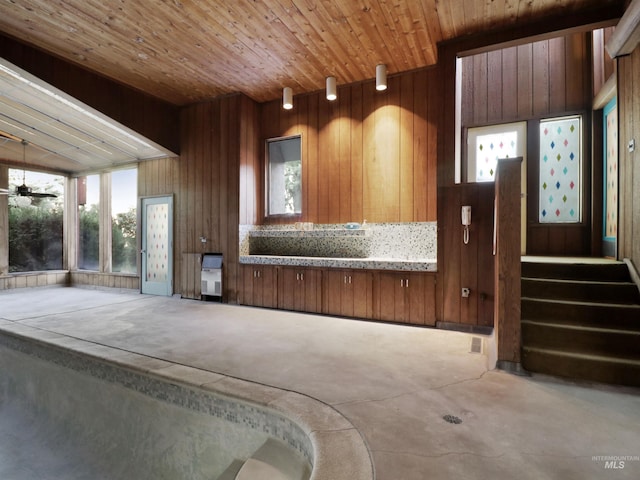 interior space featuring wooden ceiling, ceiling fan, and wooden walls