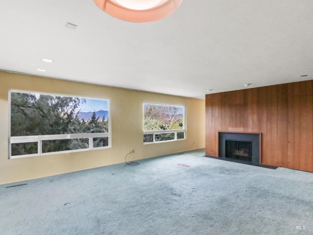 unfurnished living room featuring wooden walls and carpet flooring