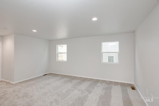 unfurnished room with recessed lighting, visible vents, light carpet, and baseboards