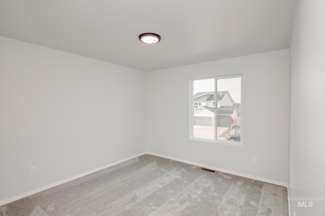 carpeted spare room with baseboards and visible vents