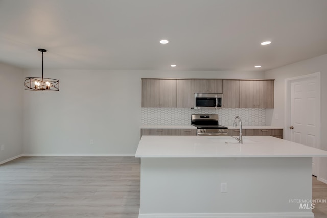 kitchen featuring light countertops, backsplash, appliances with stainless steel finishes, a sink, and modern cabinets