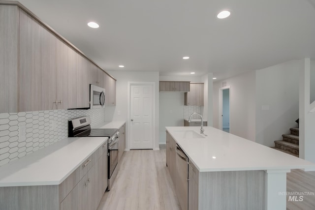 kitchen featuring light wood-style floors, modern cabinets, stainless steel appliances, and a sink