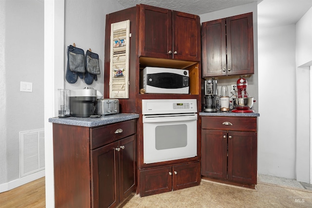 360 N 700 W, Paul, ID 83347 - kitchen featuring white appliances, reddish brown cabinets, baseboards, and dark countertops