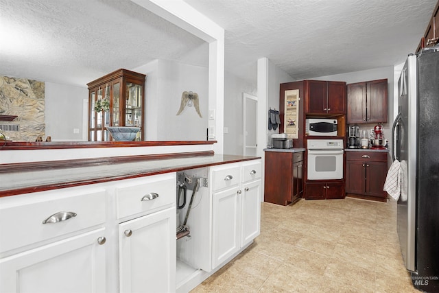 360 N 700 W, Paul, ID 83347 - kitchen featuring white appliances, a textured ceiling, and white cabinetry
