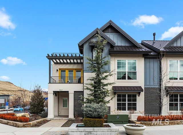 view of front of home featuring metal roof, a standing seam roof, board and batten siding, and a balcony