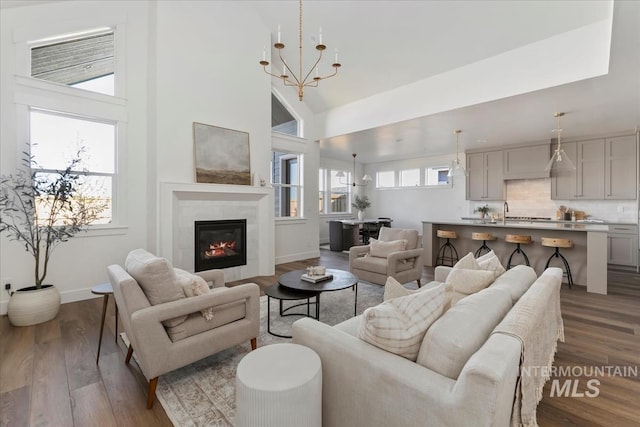 4265 W Thornapple Dr, Meridian, ID 83646 - living room featuring dark wood-type flooring, baseboards, a towering ceiling, a tiled fireplace, and a chandelier